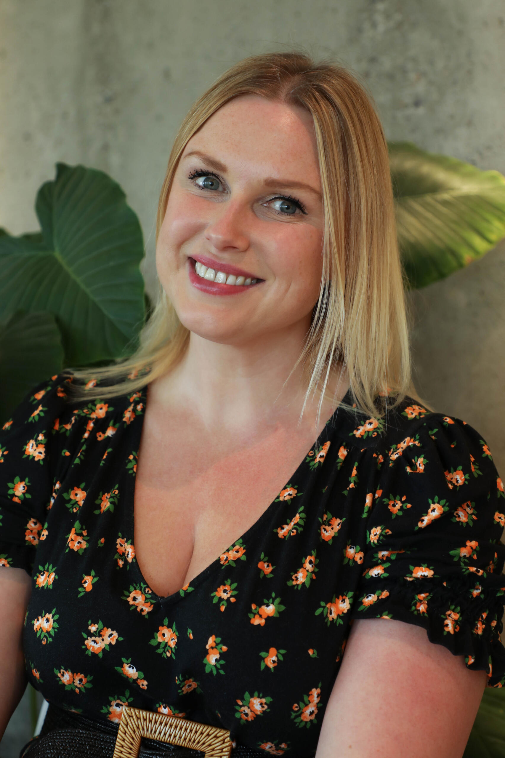 Professional headshot of Laura Winson, CEO of ZBD. She wears a floral black top and smiles warmly in front of a leafy backdrop. Her bio highlights her leadership at Zebedee and her work championing radical representation in fashion, media, and entertainmen