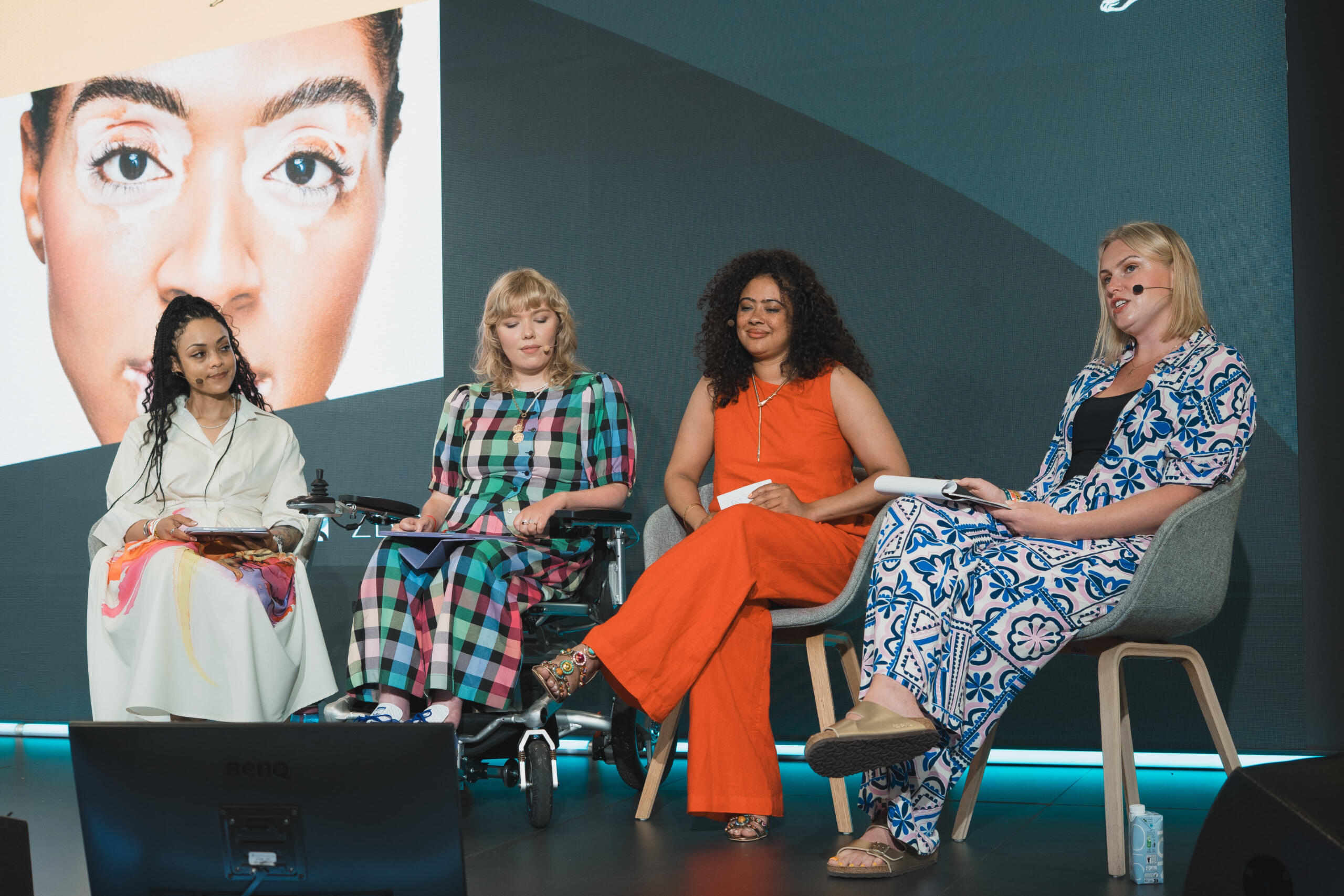 The Speakers Four women smiling side-by-side in cutout headshots. From left to right: Laura Winson in a green blazer, Charlotte Marian Pearson in an ivory jumper, Natalie Amber Freegard in a black strappy top, and Emma Lines with short blonde hair wearing a black bande