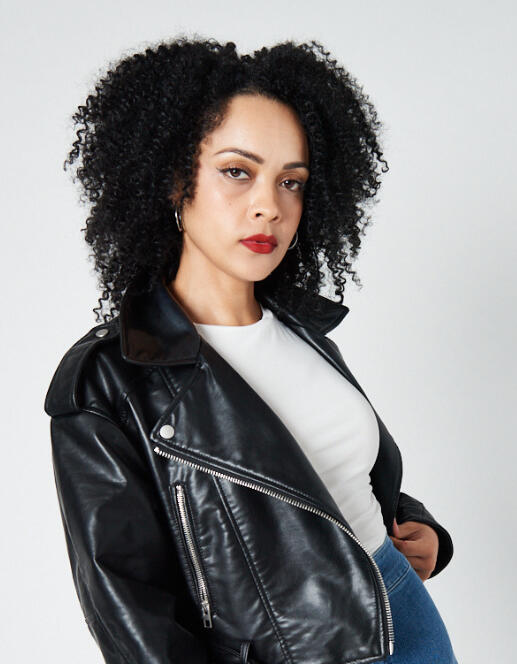 Professional portrait of Charlotte Marian Pearson wearing a black leather jacket over a white top, standing with one hand on her hip. Text beside her outlines her role as Founder of The MosaiQs and highlights her work in driving systemic change through liv